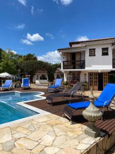 een patio met stoelen, een zwembad en een huis bij Pouso das Gerais in Tiradentes