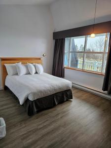 1 dormitorio con cama grande y ventana grande en Hébergement Fort Prével en Saint-Georges-de-Malbaie