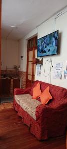 sala de estar con sofá rojo y almohadas de color naranja en Hostel The Little House Backpakers en La Paz