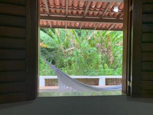 a window with a hammock looking out at a garden at Estancia Vale das Flores in Pacoti