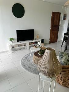 un soggiorno con TV e tavolo di Appartement avec vue panoramique de Pointe-à-Pitre a Pointe-à-Pitre