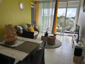 a living room with a table and a couch and a balcony at Appartement avec vue panoramique de Pointe-à-Pitre in Pointe-à-Pitre
