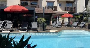 a pool with chairs and umbrellas next to a building at Le Trophée By M Hôtel Spa in Deauville