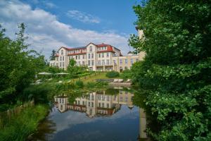 a large building next to a body of water at Naturresort & Spa Schindelbruch in Stolberg i. Harz