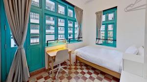 a bedroom with green windows and a bed and a desk at Habyt Bridges - 6-8 Wa In Fong Street in Hong Kong