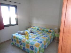 a bedroom with a bed with a yellow and blue blanket at Village La Canzone del Mare in Vieste