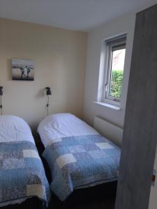 Duas camas num pequeno quarto com uma janela em libelle em Sint Nicolaasga