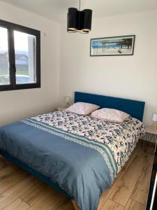 um quarto com uma cama com uma cabeceira azul e uma janela em Maison moderne em Murianette