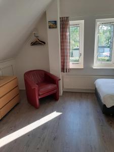 a bedroom with a red chair and a bed at libelle in Sint Nicolaasga