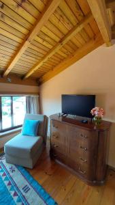 uma sala de estar com uma televisão, uma cadeira e uma cómoda em Alpendre em Guimarães