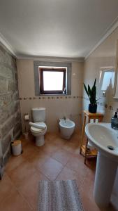 uma casa de banho com um WC, um bidé e um lavatório. em Alpendre em Guimarães