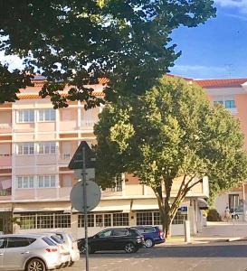 a tree in front of a building with parked cars at Atlantic Waves Accommodation in Carcavelos
