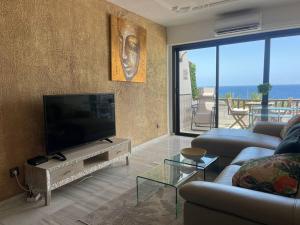 Una sala de estar con un televisor de pantalla plana y un sofá. en Sia Bungalow Sunset View, en Adeje