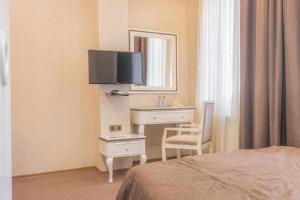 Habitación de hotel con cama, escritorio y TV. en Maestro Hotel en Bakú