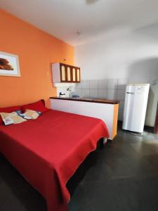 1 dormitorio con cama roja y nevera en Suites Americanas Em Jaconé, en Jaconé