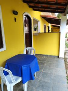 une maison jaune avec une table et des chaises bleues dans l'établissement Suites Americanas Em Jaconé, à Jaconé