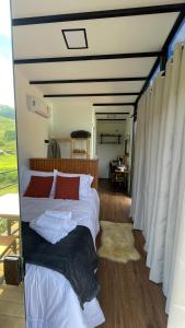 a bedroom with a bed with white sheets and red pillows at Villa Trentino Chalé Pirineus in Teodoros