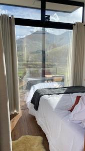 a bedroom with a bed and a large window at Villa Trentino Chalé Pirineus in Teodoros