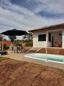 einen Pool mit Sonnenschirm, Tisch und Stühlen in der Unterkunft Rancho Teixeira in Alexânia