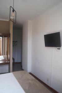 1 dormitorio con TV de pantalla plana en la pared en Hotel Chique Aliados en Oporto