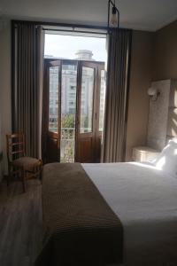 a hotel room with a bed and a large window at Hotel Chique Aliados in Porto