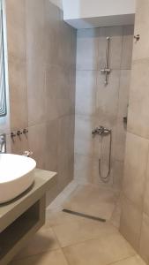 une salle de bain avec douche et lavabo dans l'établissement Onar View Apartment, à Néa Péramos