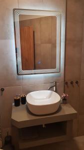 La salle de bains est pourvue d'un lavabo et d'un grand miroir. dans l'établissement Onar View Apartment, à Néa Péramos 39 autres photos