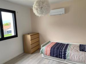 um quarto com uma cama, uma cómoda e um candeeiro em Maison moderne em Murianette