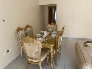 uma mesa de jantar com cadeiras, uma mesa amarela e uma espreguiçadeira em Golf Mews Inspired Living em Benin City
