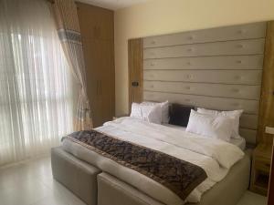 a bedroom with a large bed with a large headboard at Golf Mews Inspired Living in Benin City