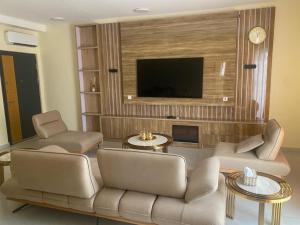 a living room with a couch and chairs and a television at Golf Mews Inspired Living in Benin City