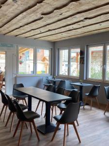 uma sala de jantar com mesas, cadeiras e janelas em Demizson Vendégház em Tokaj