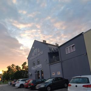 a building with cars parked in a parking lot at Apartman Vitas in Slavonski Brod