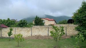 eine Backsteinmauer mit einem Haus dahinter in der Unterkunft Sheki Guest House in Şəki