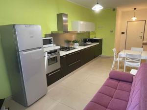 a kitchen with a white refrigerator and a purple couch at Casa vacanze Da Maria in Grottammare
