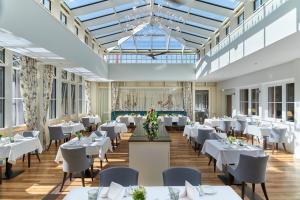 a dining room with white tables and chairs at Naturresort & Spa Schindelbruch in Stolberg