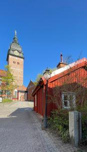 czerwony budynek z wieżą zegarową i światłem ulicznym w obiekcie Historical idyll from the 17th century w mieście Strängnäs