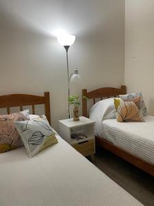 a bedroom with two beds and a lamp on a table at Habitación privada en apto cat friendly in Montevideo