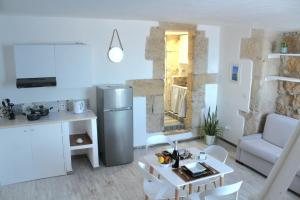 a kitchen and living room with a table and a refrigerator at Brezza Marina Ortigia in Siracusa