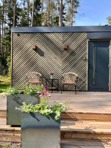 a shed with two chairs on a wooden deck at Mustika Mirror minivilla saunaga in Kärdla