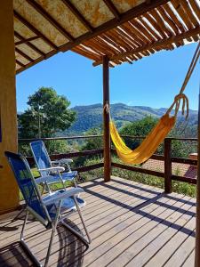 two chairs and a hammock on a deck with a view at Cafezal em Flor Turismo e Cafés Especiais in Monte Alegre do Sul