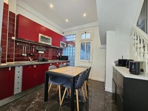 uma cozinha com armários vermelhos e uma mesa de madeira em DEAUVILLE Maison plein centre, ideale famille ! em Deauville