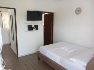a white bedroom with a bed and a flat screen tv at Coral Village Toby in Santa Bárbara de Samaná