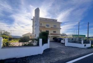 a large white building with a fence and a parking lot at Pens&atilde;o Repouso do Peregrino in Paredes de Coura