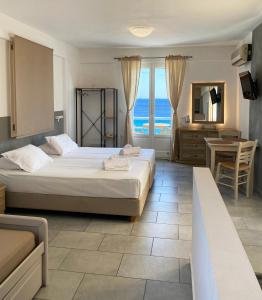 a bedroom with two beds and a view of the ocean at Agnadi Syros Beachfront Studios & Rooms in Megas Yialos-Nites