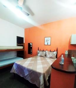 1 dormitorio con 1 cama con pared de color naranja en Suites Americanas Em Jaconé, en Jaconé