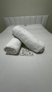 Quintal do forte في برايا جراندي: سرير عليه بطانيات بيضاء ومناشف