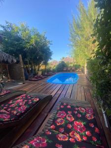 a wooden deck with two blankets and a swimming pool at Caju Bangalôs in Ponta do Anel