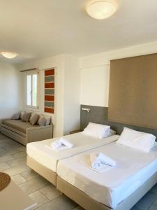 um quarto com duas camas e um sofá em Agnadi Syros Beachfront Studios & Rooms em Megas Gialos - Nites