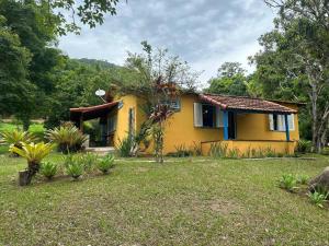 una casa gialla in un cortile con un cortile di Chalé com 2 quartos na Beira do Lago Pet Friendly a Posse